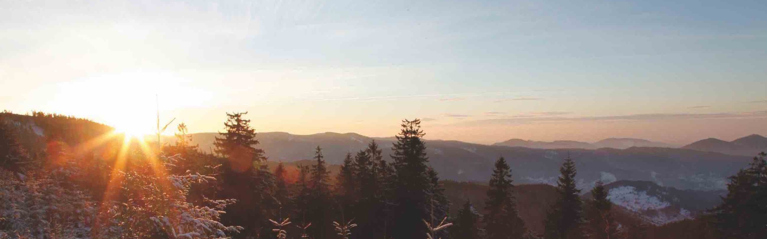 Das Bild zeigt eine Panoramasicht über die Schwarzwaldberge im Winter bei Sonnenaufgang