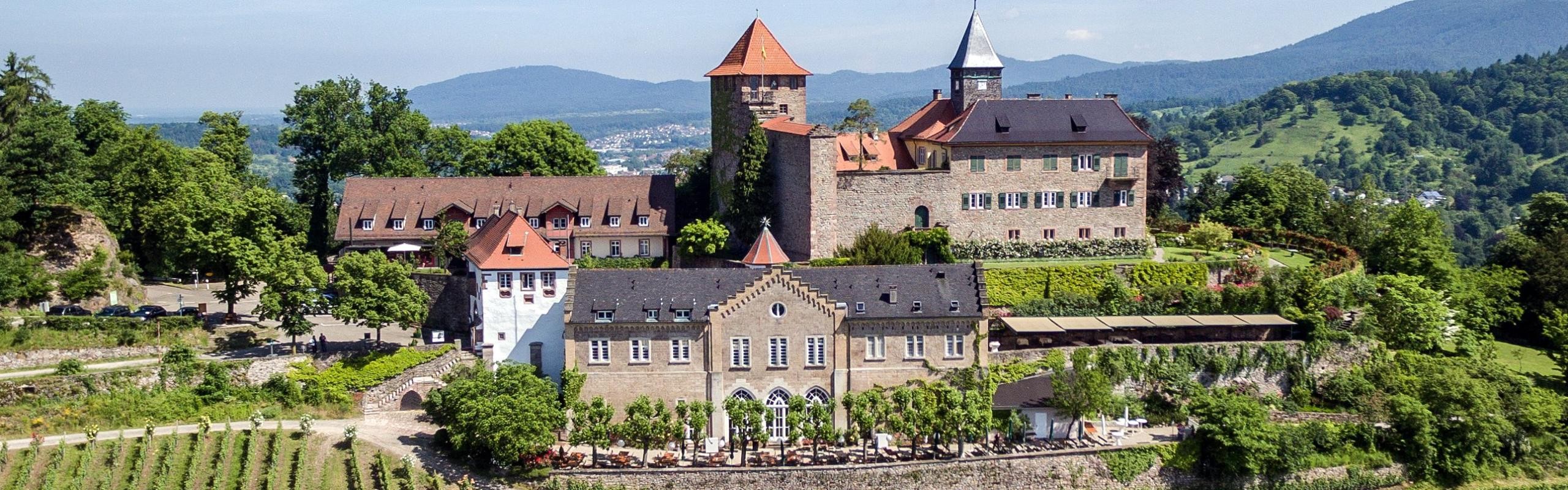 Schloss Eberstein in Gernsbach Das Bild zeigt eine Luftaufnahme vom Schloss Eberstein mit Weinberg und Schwarzwaldbergen im Hintergrund