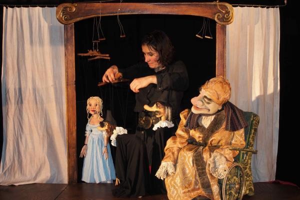 Eine Frau präsentiert zwei Puppentheaterfiguren auf der Bühne
