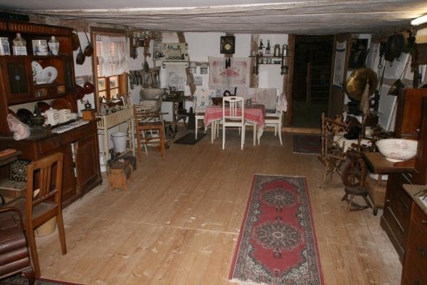Das Bild eine alte Müllerstube mit Holzfußboden, Teppich und alten Möbelstücken wie Tisch, Stühle, Schränke, Waschtisch und Wanduhr