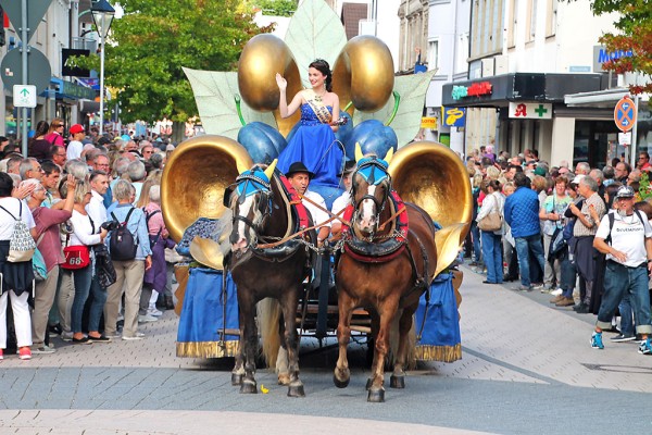 Das Bild zeigt die winkende Bühler Zwetschgenkönigin auf einem Motivwagen, gezogen von zwei Pferden während des Festumzuges, der von vielen Besuchern bestaunt wird