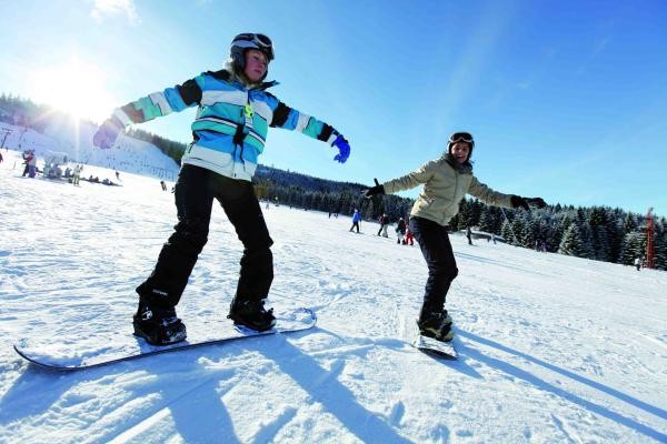 Zwei Personen auf dem Snowboard im Schnee